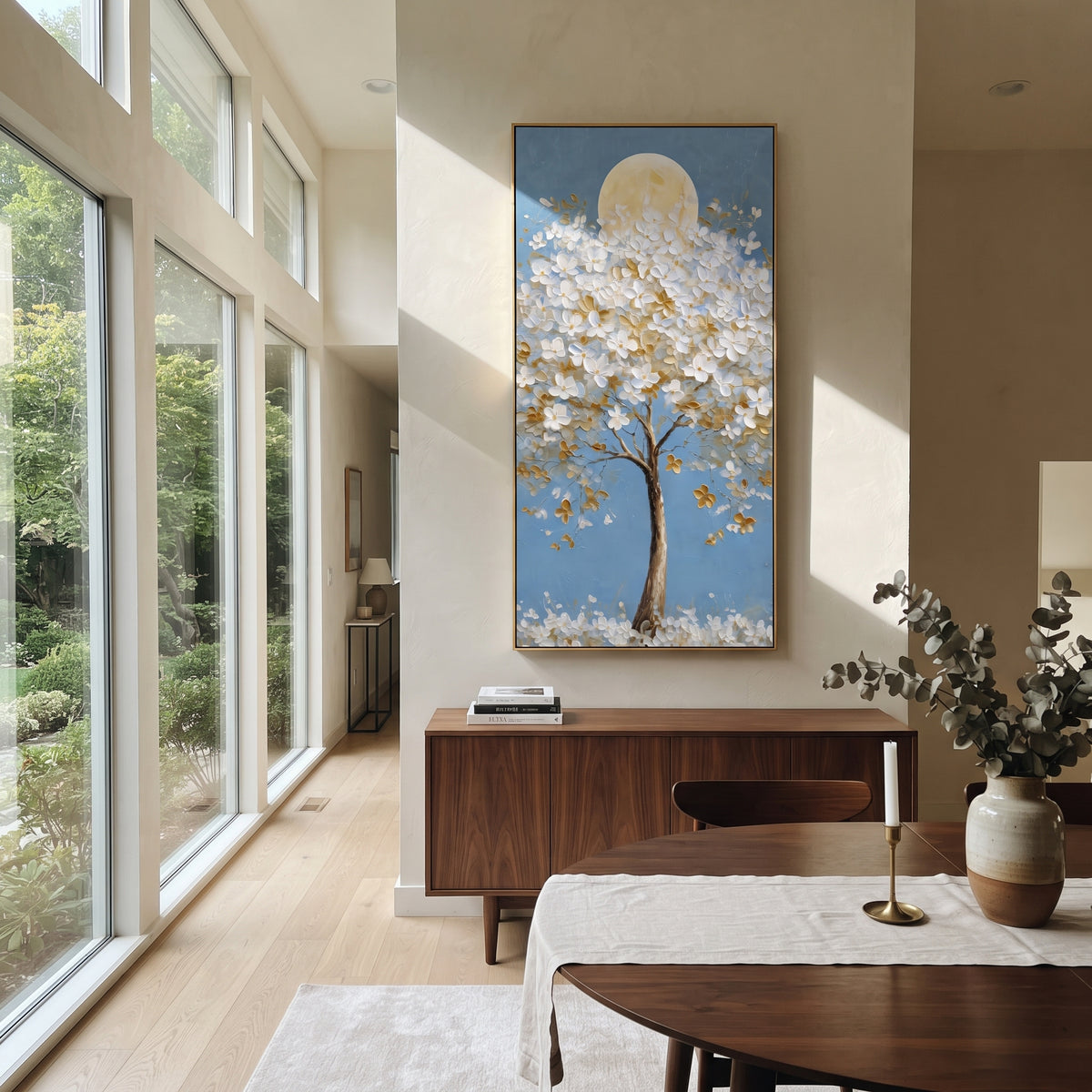 "Moonlit White Blossom Tree Painting" focuses on atmosphere, surface movement, and sculptural heavy impasto craftsmanship rather than a fixed literal storyline. The composition uses this hand-painted vertical canvas presents a tall tree covered in raised white blossoms and golden leaves, set before a soft round moon on a clear blue background as the visual anchor, while layered palette-knife paint, raised plaster-like texture, and softened brush movement create tactile depth across the canvas.