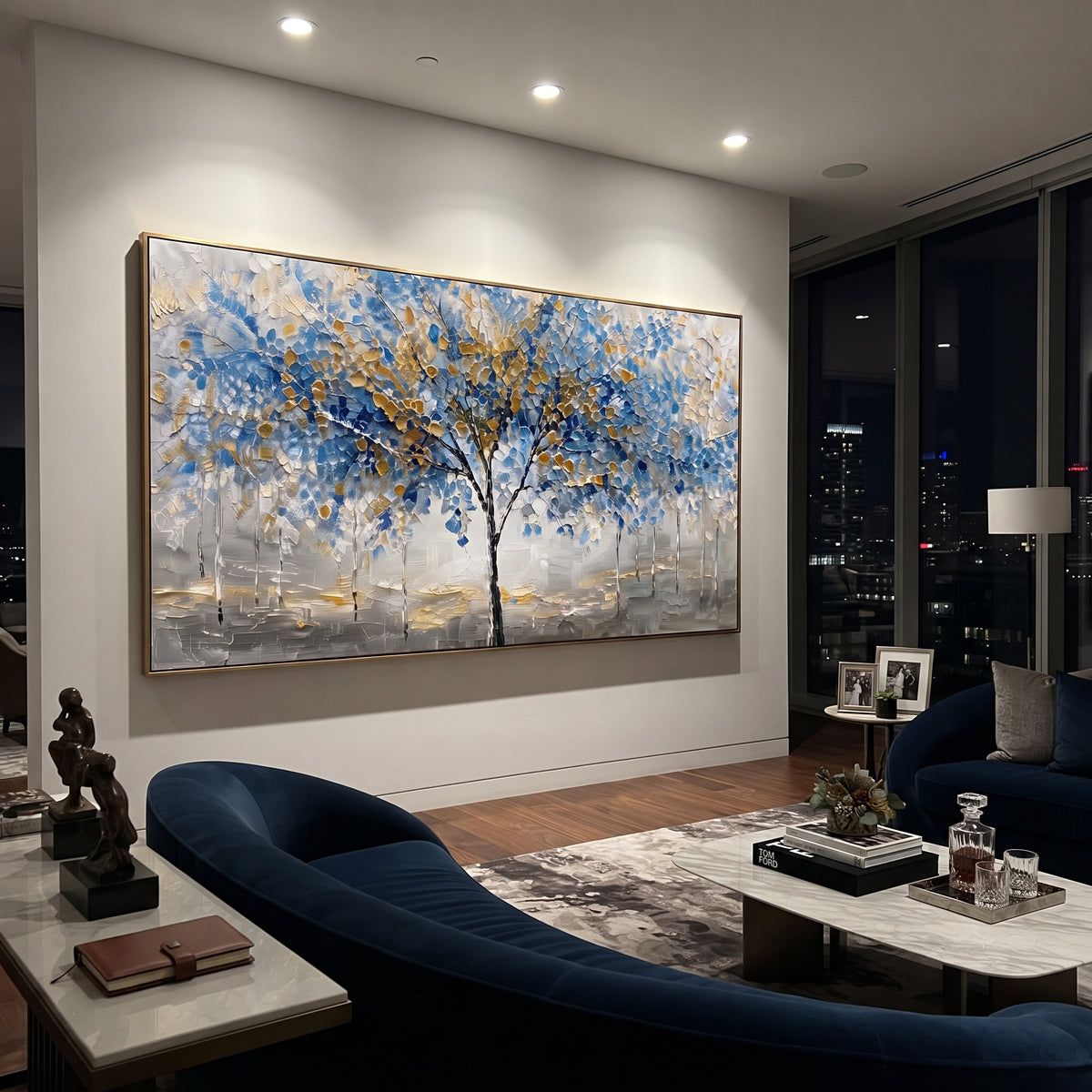 "Blue Gold Tree Painting" focuses on atmosphere, surface movement, and sculptural heavy impasto craftsmanship rather than a fixed literal storyline. The composition uses this hand-painted panoramic canvas presents a central black tree with blue and golden leaves over a grey white textured ground, with slender pale trees in the background as the visual anchor, while layered palette-knife paint, raised plaster-like texture, and softened brush movement create tactile depth across the canvas.