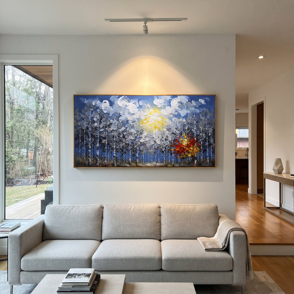 "Blue Forest Sunburst Painting" focuses on atmosphere, surface movement, and sculptural heavy impasto craftsmanship rather than a fixed literal storyline. The composition uses this hand-painted panoramic canvas features a blue birch forest under swirling white clouds and a yellow sun, with one red orange autumn tree glowing against cool grey textured woods as the visual anchor, while layered palette-knife paint, raised plaster-like texture, and softened brush movement create tactile depth across