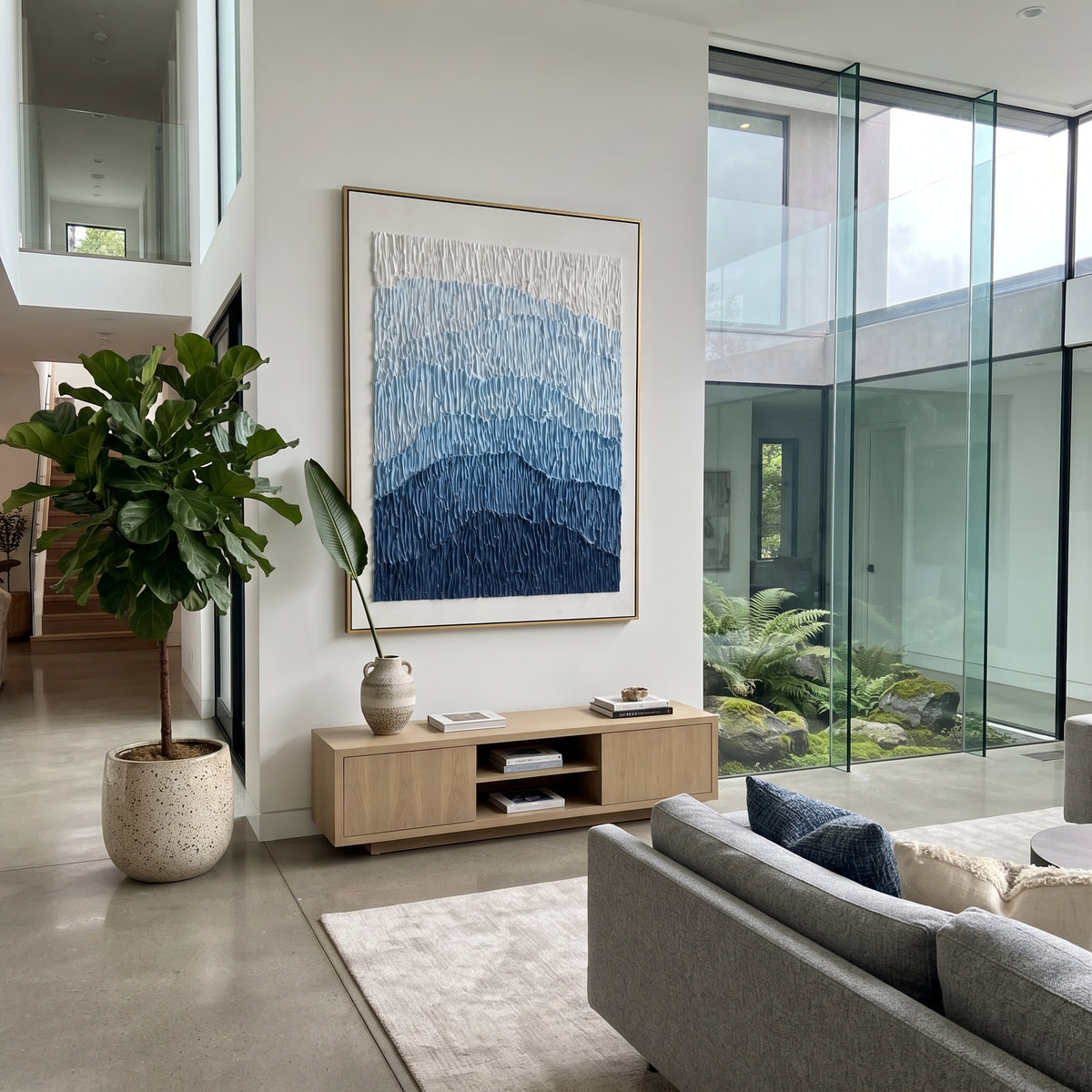 This blue mountain gradient relief painting uses stacked blue bands and vertical combed plaster texture to suggest distant mountains, glaciers, or rolling terrain. Its restrained blue-white palette gives the vertical canvas a calm architectural presence.