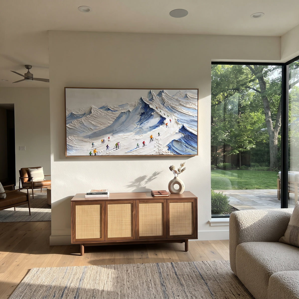 Blue Ridge Ski Queue focuses on a group of skiers lined along a blue mountain ridge before a bright alpine backdrop. The artwork shows a winter ski scene built from the actual image: visible downhill figures, curved snow tracks, raised ridgelines, and alpine space arranged in a wide composition. The blue, white, yellow palette gives the piece a cold mountain atmosphere while the thick impasto surface creates shadows along each snowbank, ski line, and textured ridge. This is presented as