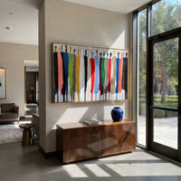 This 100% hand-painted modern abstract figurative artwork showcases a lineup of simplified vertical human forms created with thick palette-knife brushstrokes. Bold saturated hues of red, blue, green, yellow, orange and black form layered textured shapes. The dimensional impasto surface creates a striking contemporary statement for living rooms, offices, lobbies, entryways and modern commercial interiors.