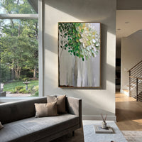 "Vertical Green White Tree Painting" focuses on atmosphere, surface movement, and sculptural heavy impasto craftsmanship rather than a fixed literal storyline. The composition uses this hand-painted vertical canvas shows a slender tree rising against a muted grey background, with dark green leaves, white and pale yellow foliage, fine branch lines, and raised textured paint concentrated through the upper canopy as the visual anchor, while layered palette-knife paint, raised plaster-like texture