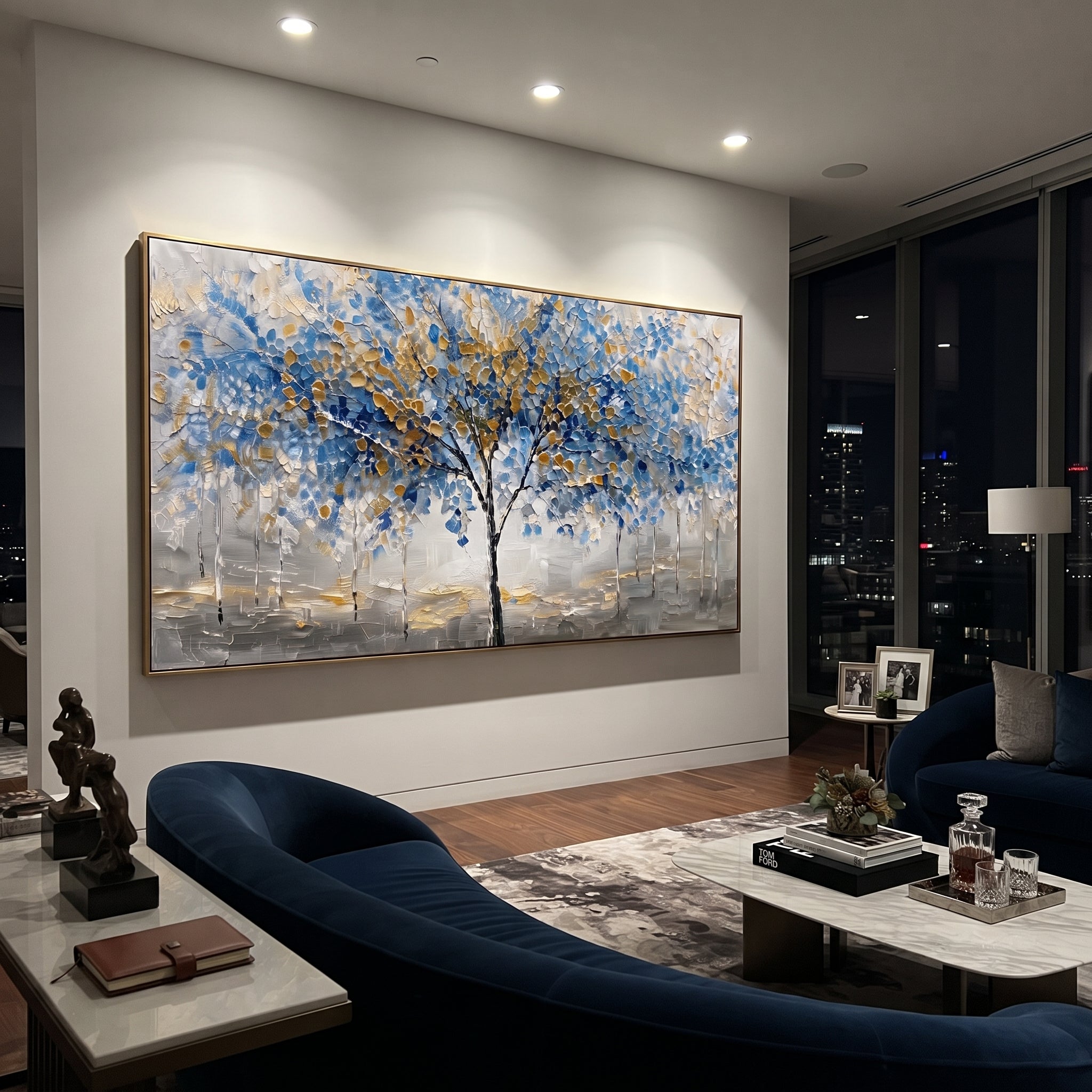 "Blue Gold Tree Painting" focuses on atmosphere, surface movement, and sculptural heavy impasto craftsmanship rather than a fixed literal storyline. The composition uses this hand-painted panoramic canvas presents a central black tree with blue and golden leaves over a grey white textured ground, with slender pale trees in the background as the visual anchor, while layered palette-knife paint, raised plaster-like texture, and softened brush movement create tactile depth across the canvas.