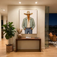 "Hands In Pockets Cowboy Painting" focuses on atmosphere, surface movement, and sculptural heavy impasto craftsmanship rather than a fixed literal storyline. The composition uses this hand-painted vertical canvas features a faceless cowboy with both hands tucked into his pockets, wearing a wide beige hat, pale sage jacket, cream shirt, and blue grey denim as the visual anchor, while layered palette-knife paint, raised plaster-like texture, and softened brush movement create tactile depth across