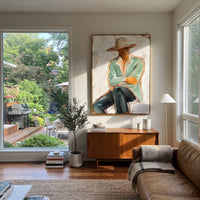 "Low Brim Cowboy Figure Painting" focuses on atmosphere, surface movement, and sculptural heavy impasto craftsmanship rather than a fixed literal storyline. The composition uses this hand-painted vertical canvas presents a faceless cowboy under a low wide beige hat, wearing a muted sage jacket and cream shirt as the visual anchor, while layered palette-knife paint, raised plaster-like texture, and softened brush movement create tactile depth across the canvas. Curated with a balanced green