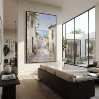 "Blue Cliffside Bay Painting" focuses on atmosphere, surface movement, and sculptural heavy impasto craftsmanship rather than a fixed literal storyline. The composition uses this hand-painted Mediterranean canvas features steep coastal cliffs, hillside village, deep blue water, floral foreground, textured sky, built with raised palette-knife texture, layered brushwork, and luminous coastal color as the visual anchor, while layered palette-knife paint, raised plaster-like texture, and softened