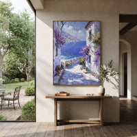 "Whitewashed Bloom Lane Painting" focuses on atmosphere, surface movement, and sculptural heavy impasto craftsmanship rather than a fixed literal storyline. The composition uses this hand-painted Mediterranean canvas features whitewashed stone lane, cascading pink bougainvillea, blue sea opening, sunlit village walls, built with raised palette-knife texture, layered brushwork, and luminous coastal color as the visual anchor, while layered palette-knife paint, raised plaster-like texture, and