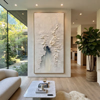 White Fragmented Plaster Relief focuses on this hand-painted vertical textured canvas features a mostly white fragmented plaster surface with raised cracked texture, fine scraped marks, and a muted blue-grey vertical accent. The composition is described from the actual main image, so the visible subject, color balance, spacing, and surface movement stay specific to this product instead of reading like a batch title. Raised palette-knife layers, sculpted impasto ridges, softened brush