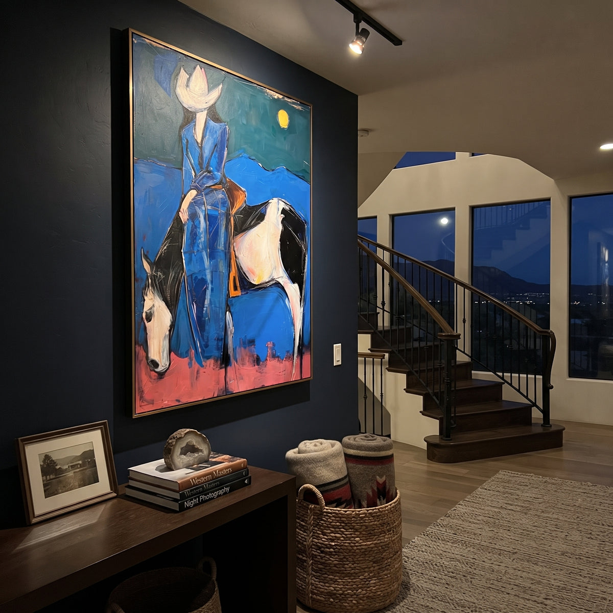 Midnight Blue Horse Rider is written from the actual artwork image, focusing on a blue-clad rider on a white horse beneath a moon over dark desert hills. The composition is built from specific visible details: white horse, blue rider clothing, crescent-like moon, dark hill line, pink ground, and night western mood. The vertical composition keeps attention on white horse, blue rider clothing, crescent-like moon, dark hill line, pink ground, and night western mood, using open ground, cropped