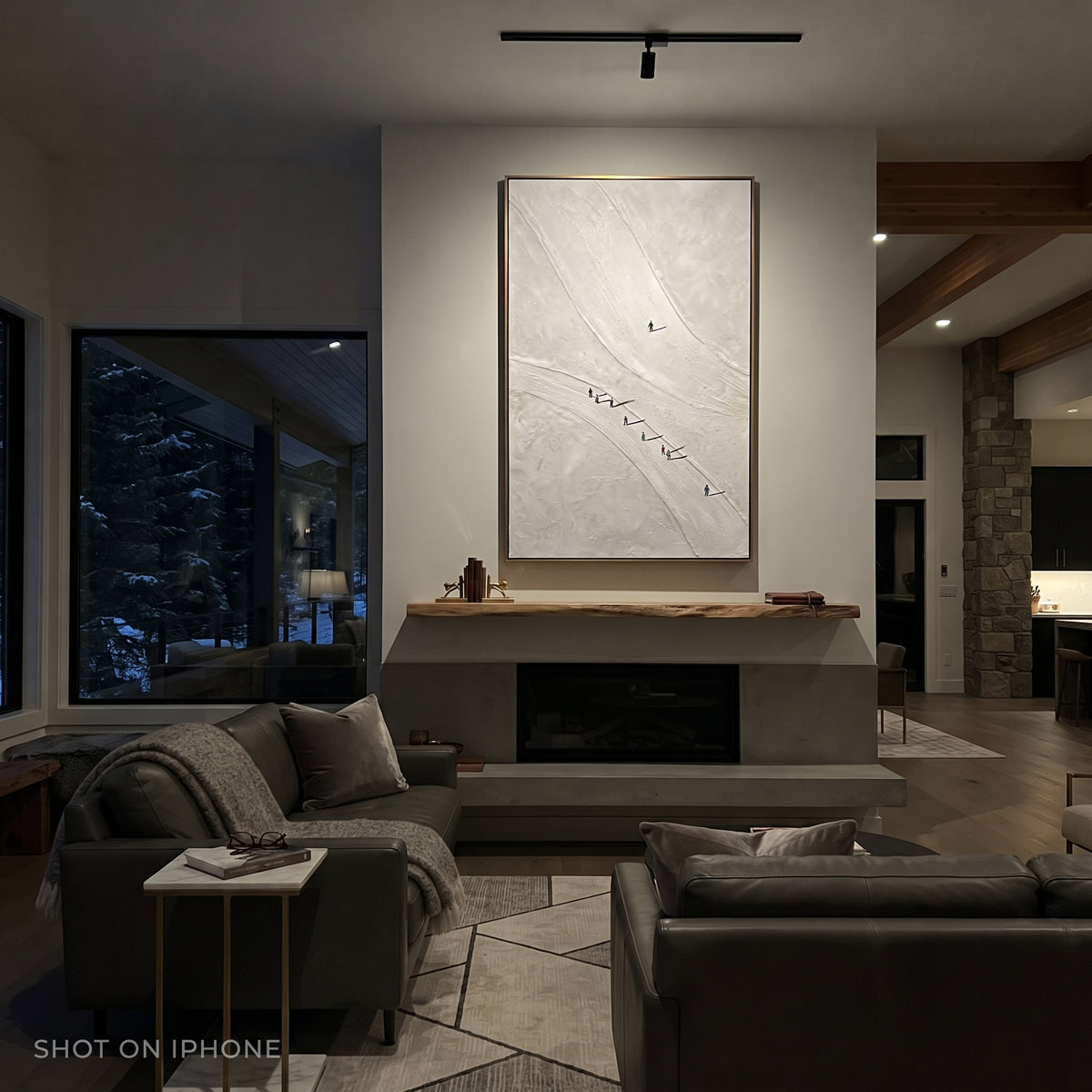 Carved Snow Trail With Pine Shadows focuses on soft gray snowfields broken by colorful skiers and thick ridge texture. The artwork shows a winter ski scene built from the actual image: visible downhill figures, curved snow tracks, raised ridgelines, and alpine space arranged in a tall composition. The white, black, gray palette gives the piece a cold mountain atmosphere while the thick impasto surface creates shadows along each snowbank, ski line, and textured ridge. This is presented as
