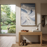 Blue Bowl Ski Descent focuses on small skiers moving below a deep blue bowl of thick sweeping snow texture. The artwork shows a winter ski scene built from the actual image: visible downhill figures, curved snow tracks, raised ridgelines, and alpine space arranged in a tall composition. The blue, white, gray palette gives the piece a cold mountain atmosphere while the thick impasto surface creates shadows along each snowbank, ski line, and textured ridge. This is presented as hand-painted