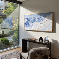 Misty Alpine Descent With Pine Shadows focuses on a forest-framed ski descent with clustered pines and winding carved tracks. The artwork shows a winter ski scene built from the actual image: visible downhill figures, curved snow tracks, raised ridgelines, and alpine space arranged in a wide composition. The white, green, blue palette gives the piece a cold mountain atmosphere while the thick impasto surface creates shadows along each snowbank, ski line, and textured ridge. This is presented as