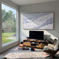 Ice Ski Tracks With Pine Shadows focuses on a forest-framed ski descent with clustered pines and winding carved tracks. The artwork shows a winter ski scene built from the actual image: visible downhill figures, curved snow tracks, raised ridgelines, and alpine space arranged in a wide composition. The white, beige, blue palette gives the piece a cold mountain atmosphere while the thick impasto surface creates shadows along each snowbank, ski line, and textured ridge. This is presented as