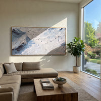 Winter Snow Basin focuses on layered snow ridges, visible ski marks, and a quiet pine border. The artwork shows a winter ski scene built from the actual image: visible downhill figures, curved snow tracks, raised ridgelines, and alpine space arranged in a wide composition. The white, black, gray palette gives the piece a cold mountain atmosphere while the thick impasto surface creates shadows along each snowbank, ski line, and textured ridge. This is presented as hand-painted textured canvas